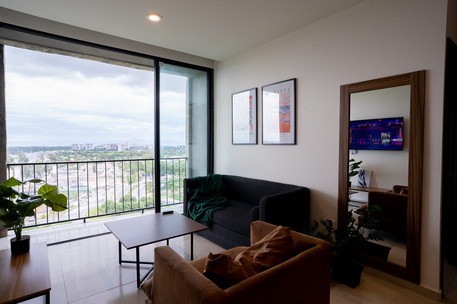 Sala con sofá, mesa, espejo y balcón con vista.