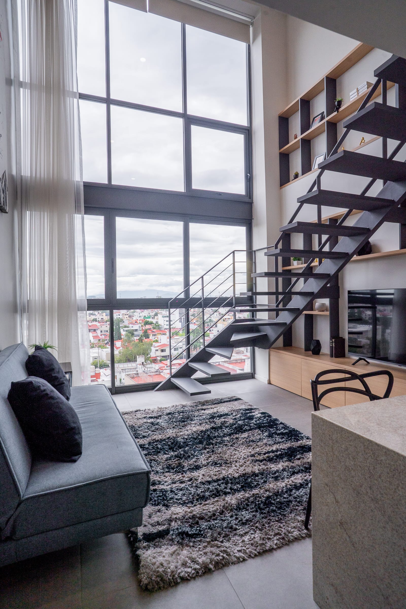 Sala de doble altura con escaleras y ventanal