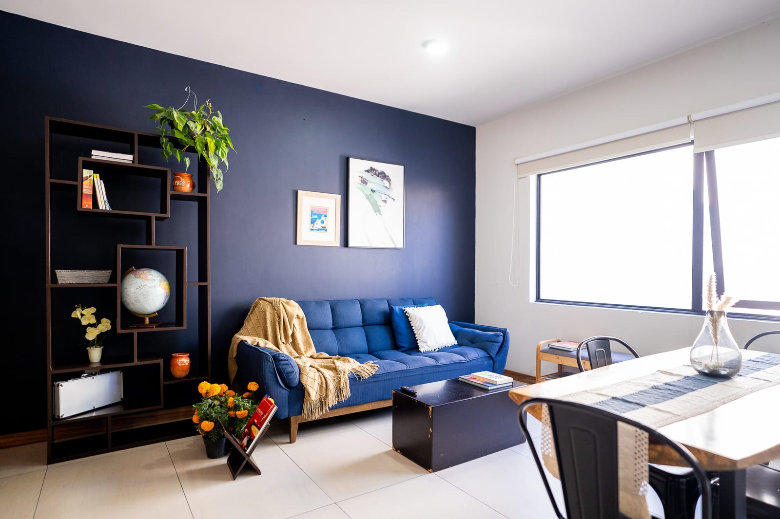 Sala comedor con sofá azul y librero oscuro